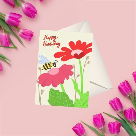 A cheerful birthday card featuring a small bee flying near two colorful flowers—one red and one pink—with handwritten 'Happy Birthday' text above. The design is simple, playful, and nature-inspired, perfect for a joyful celebration. behind the card is a white blank matching envelope visable