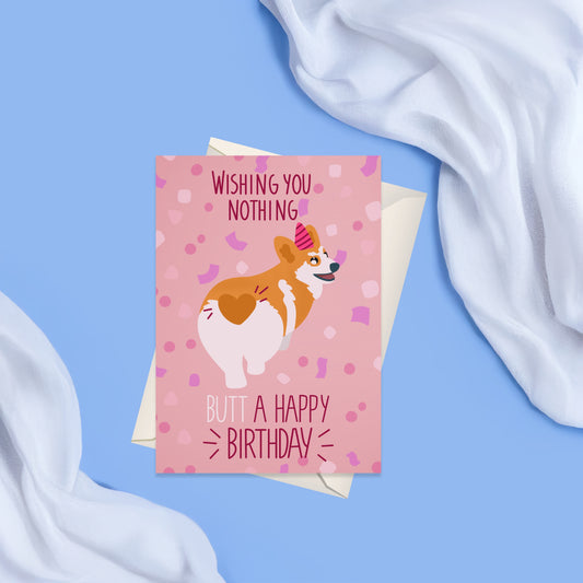 Greeting card with a pink background and pink confetti featuring a corgi dog from behind wearing a pink birthday hat. around the corgi there is in dark red the text whishing you nothing butt a happy birthday. Coming with a matching blank white envelope.