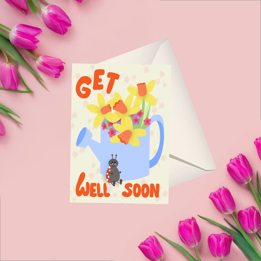 Greeting card wit a beige background featuring a blue watering can with yellow narcissus and other pink flowers comming out of it. on the bottom of the watering can is a ladybug sitting around the watering can there is the text get well soon in a bright orange color. coming with a matching white envelope