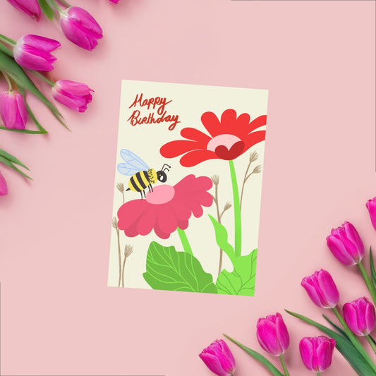 A cheerful birthday card featuring a small bee flying near two colorful flowers—one red and one pink—with handwritten 'Happy Birthday' text above. The design is simple, playful, and nature-inspired, perfect for a joyful celebration