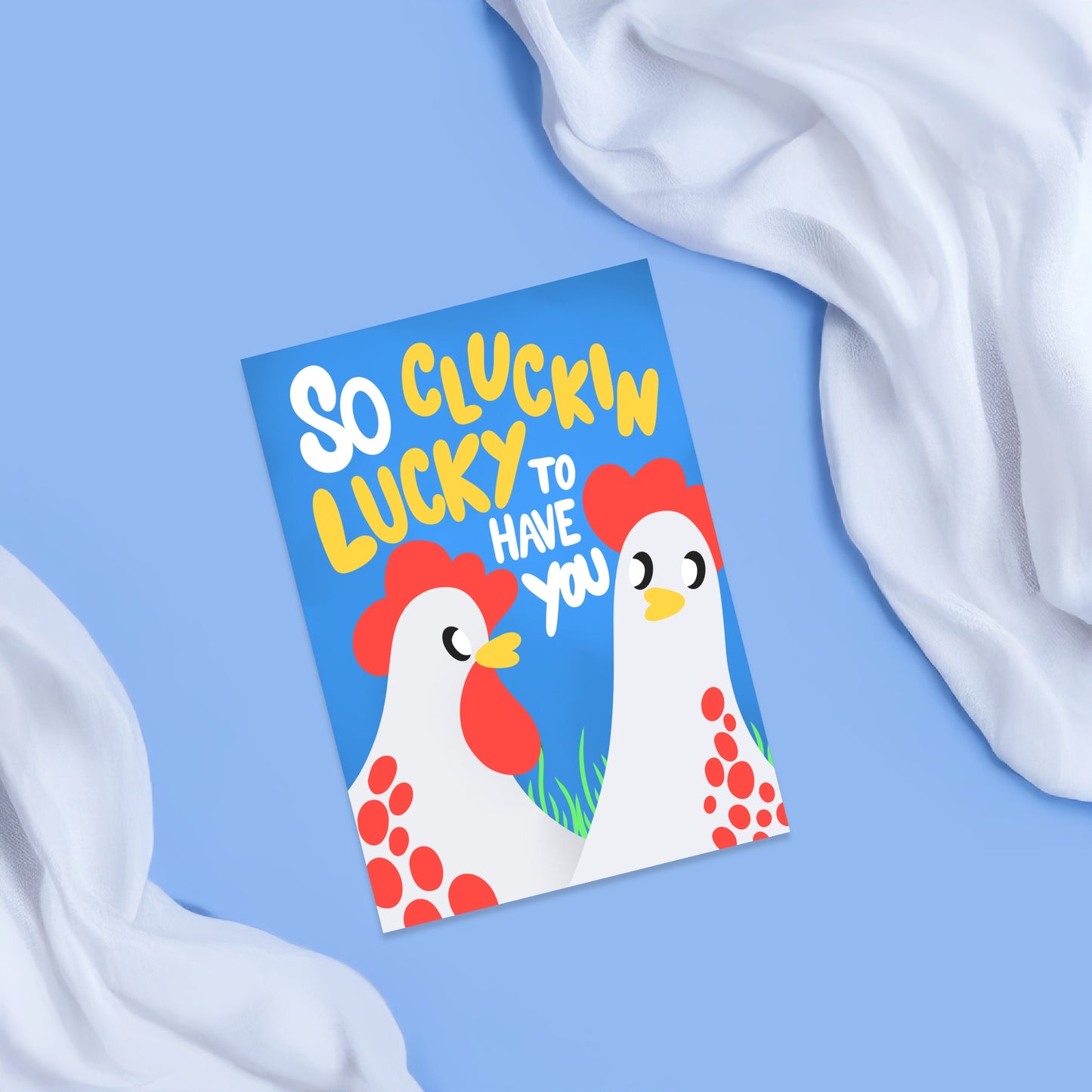 Bright blue card featuring two white chickens with red accents and a funky looking text saying I am so clucking lucky to have you 