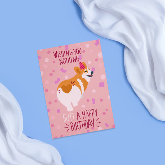 Greeting card with a pink background and pink confetti  featuring a corgi dog from behind wearing a pink birthday hat. around the corgi there is in dark red the text whishing you nothing butt a happy birthday.