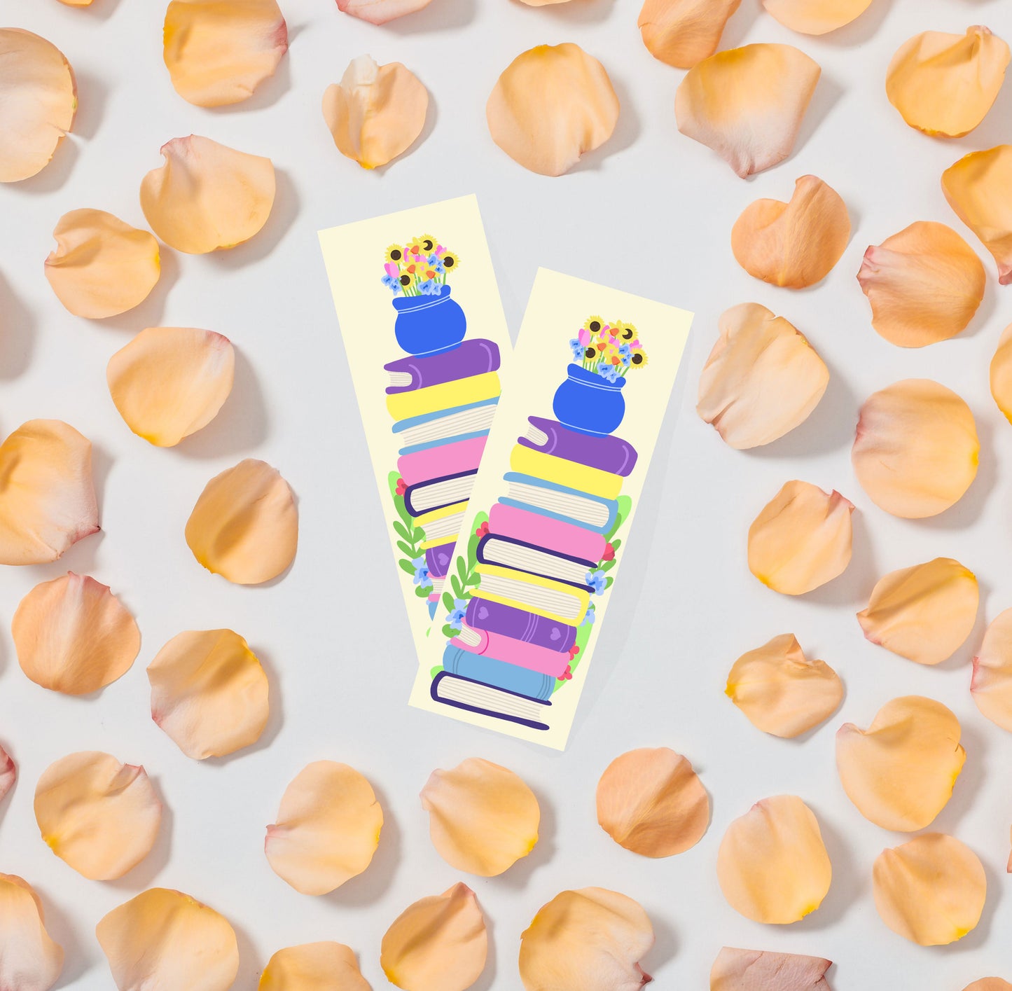 Colorful bookmark with floral design behind a stack of books on a light background with flower petals